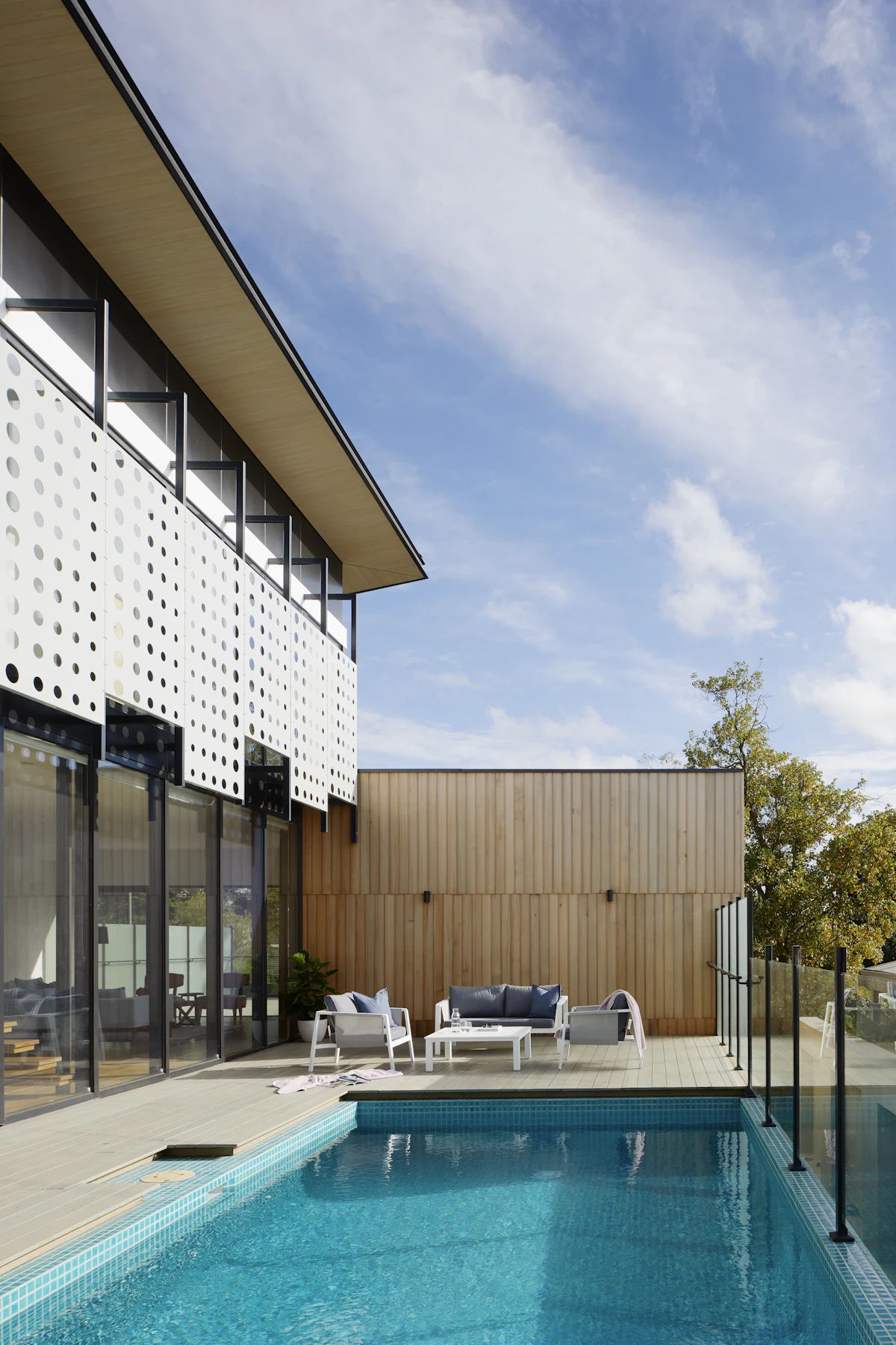 Großzügiges Pooldeck aus Thermoholz mit Lounge-Bereich vor heller Holzfassade