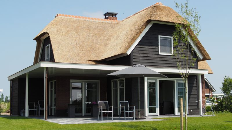 Überdachte Terrasse eines Landhauses mit Gartenmöbeln
